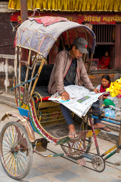 conducteur de rickshaw lisant journal à katmandou - rickshaw nepal men indian culture photos et images de collection