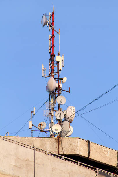 istock Telecommunication base stations network repeaters on the roof of building. The cellular communication aerial on city building roof. Cell phone telecommunication tower. Antennas on top of building. 1087212436