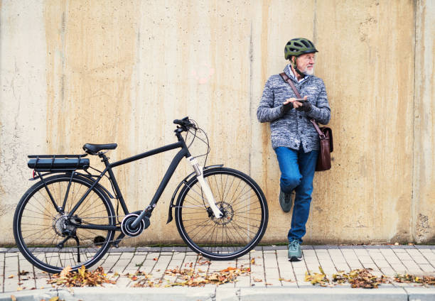 istock Active senior man with electrobike standing outdoors in town, using smartphone. 1087217210
