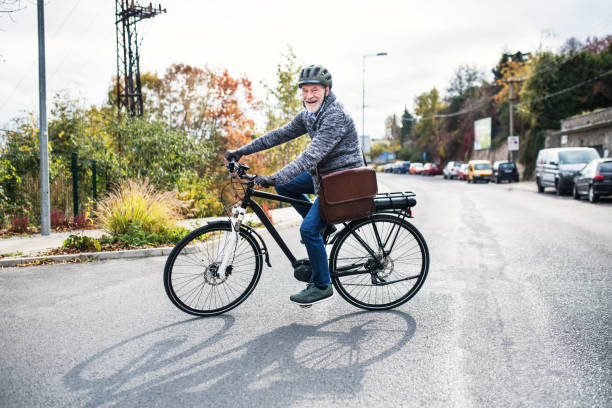 aktive ältere mann mit elektrobike radfahren im freien in der stadt. - men hat leather senior adult stock-fotos und bilder