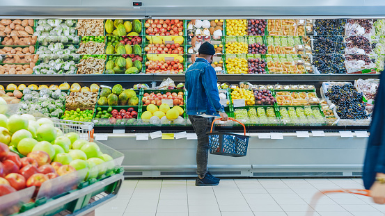 En el supermercado: feliz hombre elegante negro con compras cesta de compras de frutas y verduras en fresco de la sección de la tienda de producir. photo