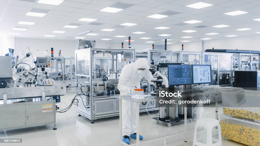 Shot of Sterile Pharmaceutical Manufacturing Laboratory where Scientists in Protective Coverall's Do Research, Quality Control and Work on the Discovery of new Medicine. Medicine Stock Photo