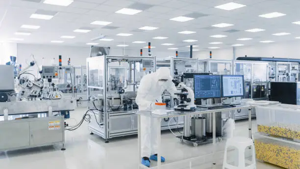 Photo of Shot of Sterile Pharmaceutical Manufacturing Laboratory where Scientists in Protective Coverall's Do Research, Quality Control and Work on the Discovery of new Medicine.