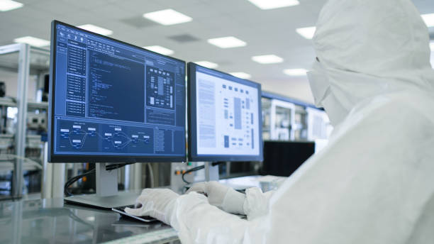 tiro de um cientistas em estéril ternos trabalhar com computadores, analisando dados forma a maquinaria industrial moderna no laboratório. processo de fabricação do produto: farmácia, semicondutores, biotecnologia. - máquina de manufactura farmacêutica - fotografias e filmes do acervo