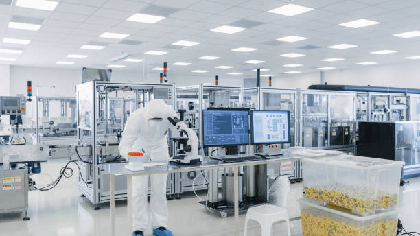 istock Shot of Sterile High Precision Manufacturing Laboratory where Scientists in Protective Coverall's Use Computers and Microscopes, doing Pharmaceutics, Biotechnology and Semiconductor Research. 1087218928