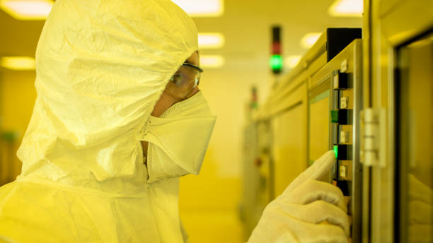 na equipe de instalações de fabricação da cientista wearing estéril, conjunto de macacão protetor acabou / programas impressora 3d industrial moderna, alta precisão manufatura de semicondutores sob processo. filtro amarelo. - máquina de manufactura farmacêutica - fotografias e filmes do acervo