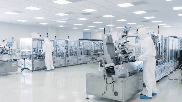 istock Sterile High Precision Manufacturing Laboratory where Scientists in Protective Coverall's Turn on Machninery, Use Computers and Microscopes, doing Pharmaceutics, Biotechnology and Semiconductor Research. 1087218940