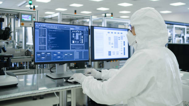 tiro de um cientistas em estéril ternos trabalhar com computadores, analisando dados forma a maquinaria industrial moderna no laboratório. processo de fabricação do produto: farmácia, semicondutores, biotecnologia. - máquina de manufactura farmacêutica - fotografias e filmes do acervo