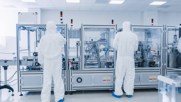 istock Manufacturing Laboratory where Scientists in Protective Coverall's Work with Industrial High Precision 3D Printing Machinery. Manufacturing Pharmaceutical / Technological / Industrial Products. 1087219020