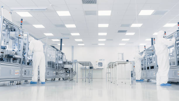 istock Team of Research Scientists in Sterile Suits Working with Computers, Microscopes and Modern Industrial Machinery in the Laboratory. Product Manufacturing Process: Pharmaceutics, Semiconductors, Biotechnology. 1087219034