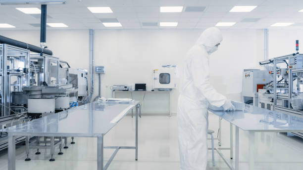 istock Scientist in Protective Suit Working with Case of Finished Product Through Laboratory. Workers in the Facility with Modern Industrial Machinery. Product Manufacturing Process: Pharmaceutics, Semiconductors, Biotechnology. 1087219110