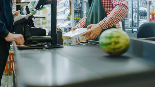 w supermarkecie: kasa counter ręce kasjera skanuje artykuły spożywcze, owoce i inne zdrowe produkty spożywcze. czyste nowoczesne centrum handlowe z przyjaznym personelem, małymi liniami i szczęśliwymi klientami. - cash register paying checkout counter cashier zdjęcia i obrazy z banku zdjęć