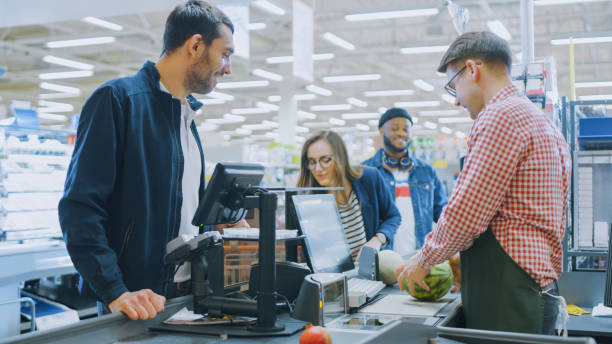 в супермаркете: касса счетчик профессиональный кассир сканирует продукты питания и продукты питания. чистый современный торговый центр. - cash register checkout counter customer shopping стоковые фото и изображения