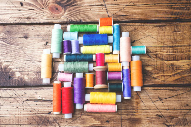 istock Colored spools of thread laid out in rows on wooden background. 1087223736