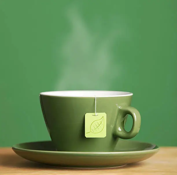 A cup of steaming hot tea in a green cup