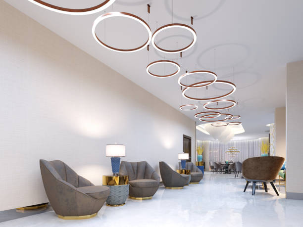 istock A modern reception area with large upholstered designer armchairs and a large chandelier of golden rings. Side tables with lamps and elegant vases. White self-leveling floor. 1087227066