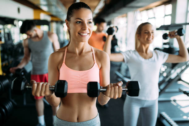 istock Young woman doing exercise with dumbbell in gym 1087227838