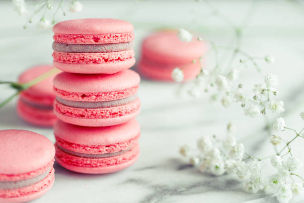 istock Stack of coral cakes macarons or macaroons on white marble with flowers besides. 1087231984