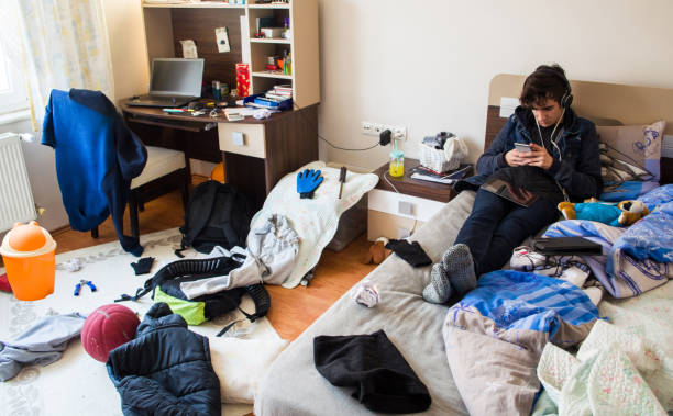 Teenager in his messy room Teenager is using smart phone in his messy room headphones plugged in photos stock pictures, royalty-free photos & images