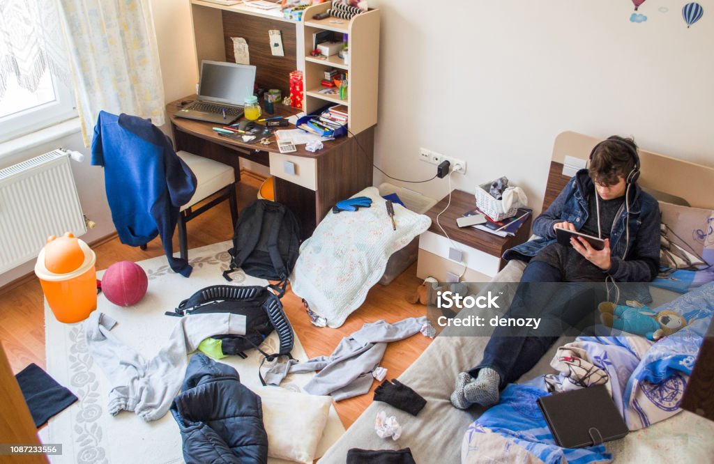Teenagers messy room Teenager is using tablet in his messy room Messy Stock Photo