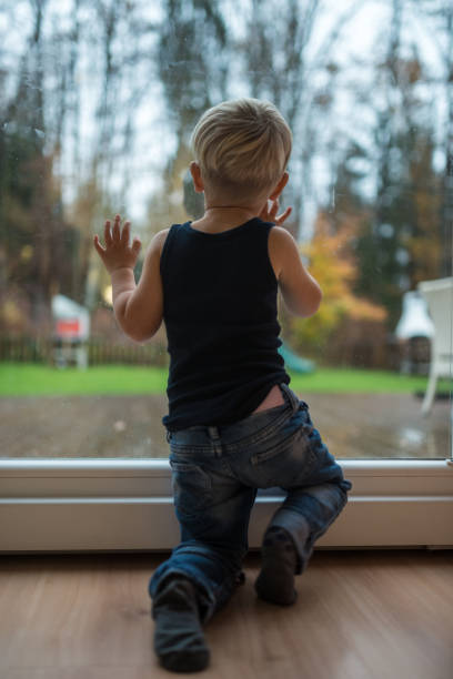 istock Toddler boy standing next to a window 1087233780