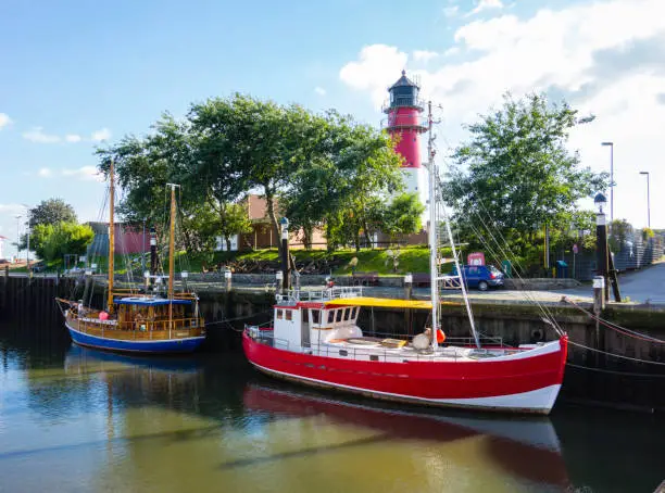 Photo of Büsumer harbor with cutters and lighthouse at blue sky Schleswig-Holstein Germany