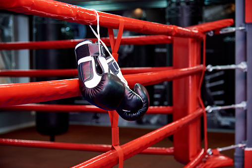 Boxing gloves in a boxing ring with bags in the gym.