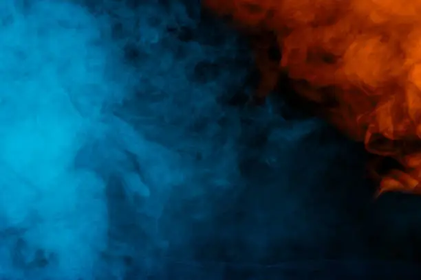 Photo of blue-orange abstraction thick and transparent cigarette vapor on a dark background