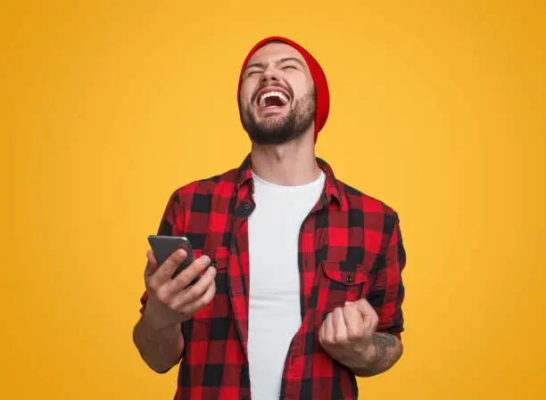 Photo of Happy male with smartphone celebrating success