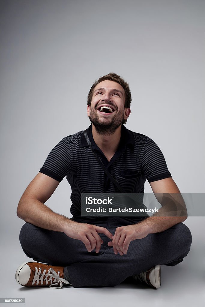 Handsome smiling man sitting cross legged on the floor Portrait of handsome man sitting with crossed legs Men Stock Photo