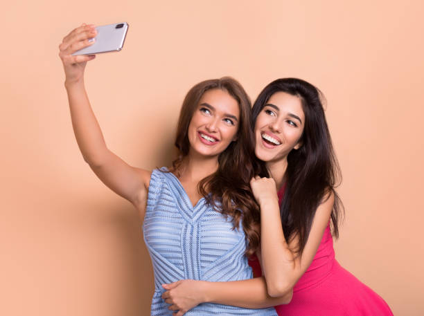 istock Two cheerful women taking selfie over pink background 1087256674