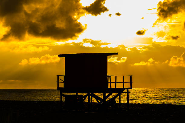 美しい日没時に小さな木の家のシルエット - lifeguard orange nature beach ストックフォトと画像