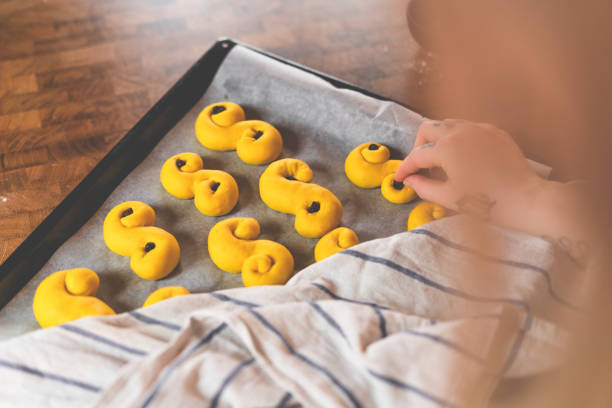 A girl is brushing eggs onto Swedish lussekatter.