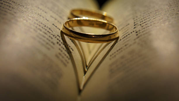 istock Gold wedding rings on an extended book 1087272426