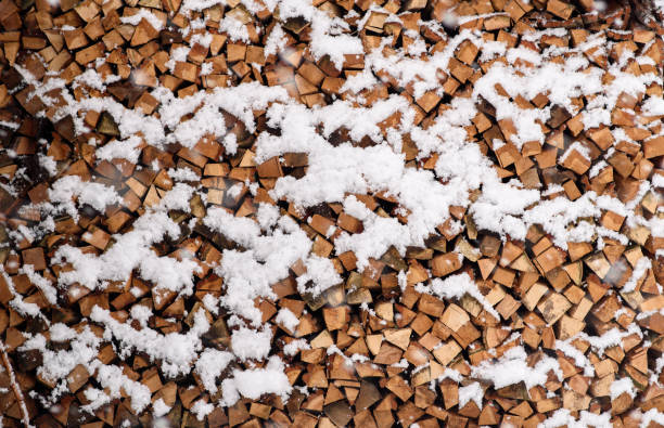 Folded chopped firewood covered with snow in winter