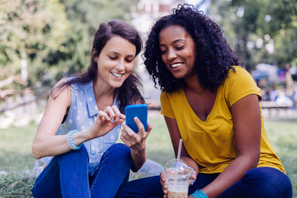 istock Mixed race girls using smartphone in the park 1087281260