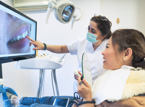 istock Female Dentist showing patient to her new teeth on computer screen 1087281520