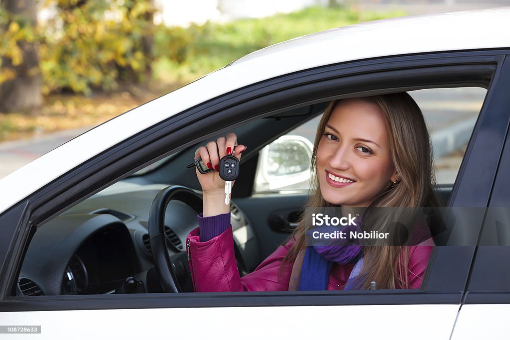 Happy owner of a new car Pretty girl sitting in her new white car and showing the key. 20-29 Years Stock Photo