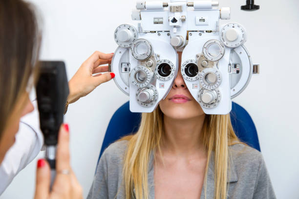 istock Young woman sitting on chair with beautiful optician standing while doing eye test in ophthalmology clinic. 1087286614