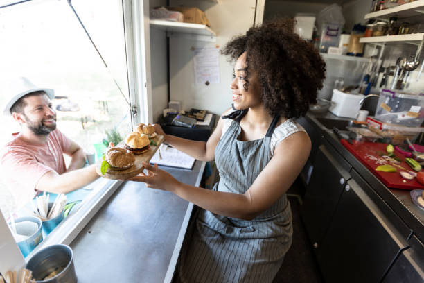 istock Smiling food van worker offering sandwiches 1087288698