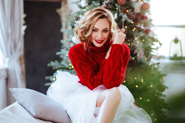 istock smiling woman in red sweater over christmas tree background 1087294434