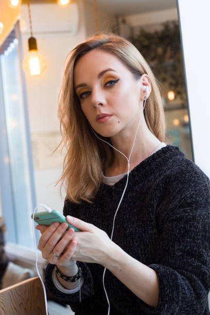istock woman in gray sweater using mobile phone with earphones 1087298450