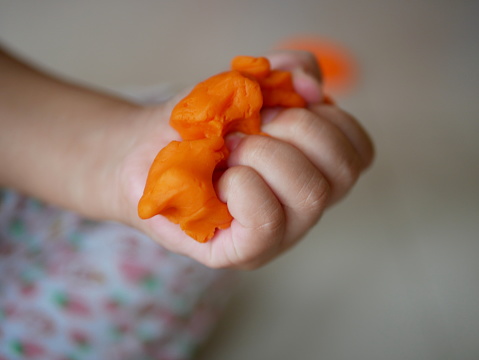 Close up of little baby's hands squeezing playdough - playing dough promotes baby's creativity, imagination, and fine motor skill development