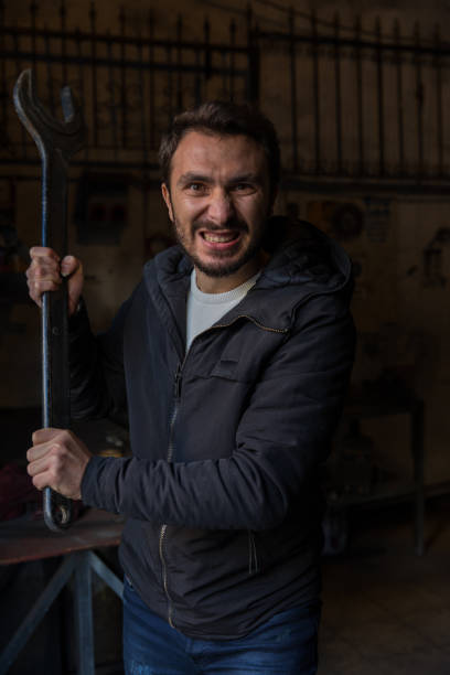 istock Masochist psycho man with huge wrench in repair workshop 1087339972