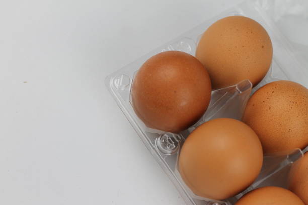 istock Close-up view of raw chicken eggs in egg box on white white background 1087350720