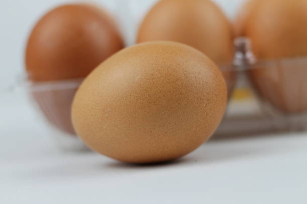 istock Close-up view of raw chicken eggs in egg box on white white background 1087350862