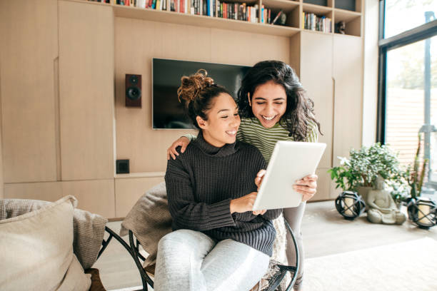 istock Two female friends laughing looking at tablet 1087352040