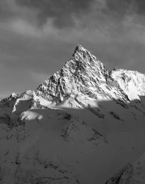 istock Black and white mountain peak in snow at winter sunset 1087352420