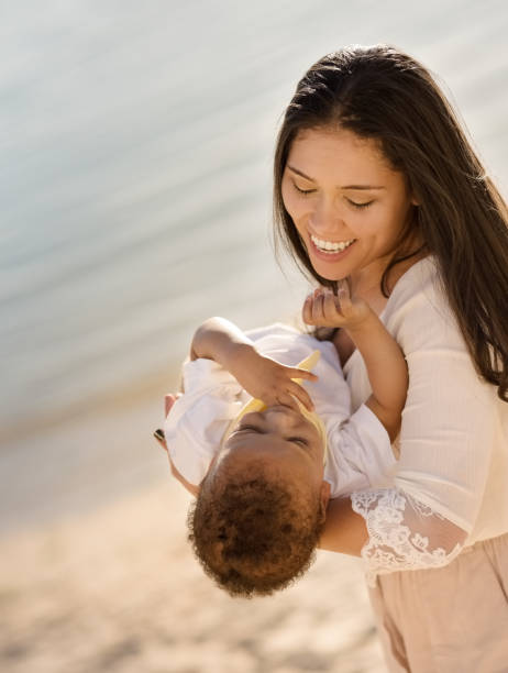 istock Woman holding her son and having fun outdoors on beach vacation. 1087352448