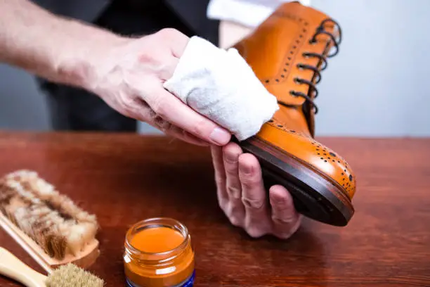 Photo of Close Up of Mans Hands Cleaning Luxury Calf Leather Brogues with Special Cloth. Horizontal image Orientation